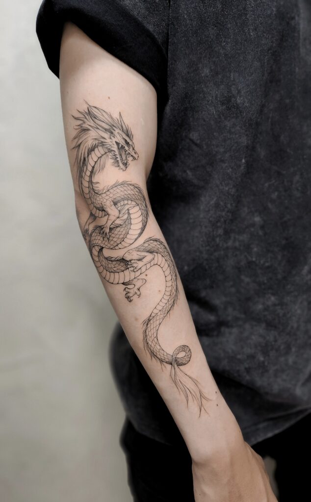 A detailed fine-line tattoo of a sinuous Eastern dragon coiling down the entire arm, from bicep to wrist, with intricately rendered scales, clawed feet, flowing whiskers, and a wispy tail fin.